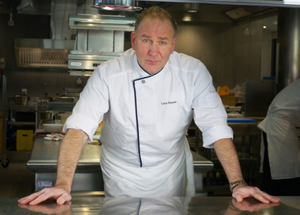Chefkock beugt sich über Küchentisch Chef appuyé sur une table de cuisine